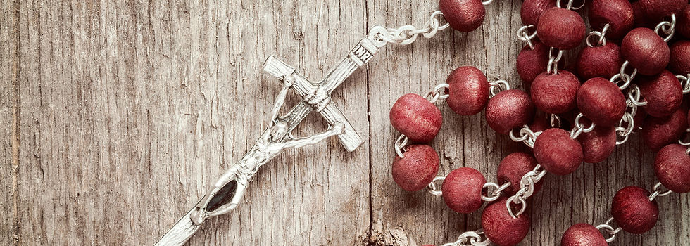 A red wooden rosary with a silver crucifix on a wooden table