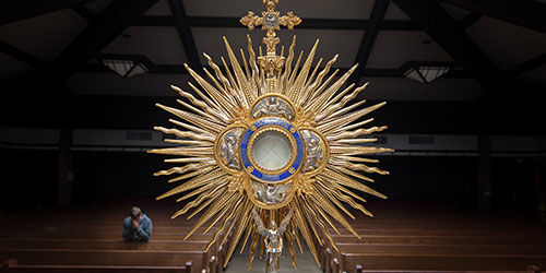 A golden monstrance with a blue center on an altar